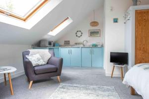 a bedroom with a chair and a kitchen with blue cabinets at A cosy hideaway on the Jurassic Coast in Lyme Regis