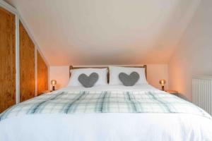 Una cama blanca con dos almohadas con corazones. en A cosy hideaway on the Jurassic Coast, en Lyme Regis