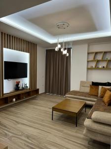 a living room with a couch and a tv at oasis apartment in Sarandë +8 photos