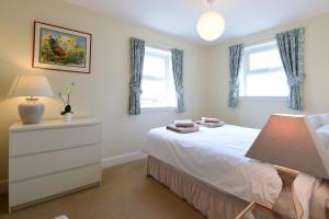 a bedroom with a bed with a dresser and two windows at Hawthorn House in Pathhead