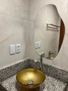 a bathroom with a gold sink and a mirror at Serra Chalés in Serra de São Bento