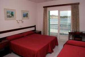 a bedroom with a red bed and a large window at Hostal Talamanca in Talamanca