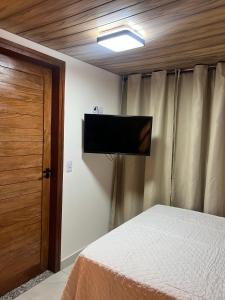 Schlafzimmer mit einem Bett und einem Flachbild-TV in der Unterkunft Serra Chalés in Serra de São Bento