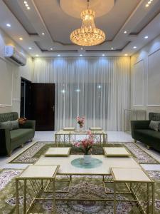 eine Lobby mit Sofas, Tischen und einem Kronleuchter in der Unterkunft شاليهات السلطان - العلا in Al-'Ula