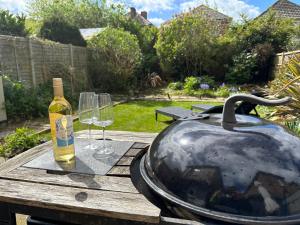 a bottle of wine and a pot and glasses on a table at The Capstone Retreat - Beautiful Detached Family Home By Coastline Retreats, Arcade Machine, Parking, BBQ in Bournemouth