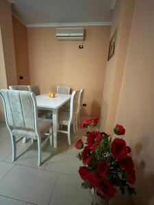 een eetkamer met een tafel en stoelen en rode rozen bij Reka Apartment in Tirana