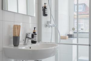 uma casa de banho branca com um lavatório e um espelho em Modernes Apartment in top Lage komfortabel eingerichtet mit Arbeitsplatz und Küche - Geibelsuite em Hanôver