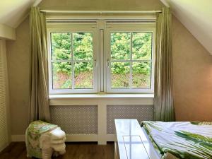 1 Schlafzimmer mit 2 Fenstern, einem Bett und einem Tisch in der Unterkunft Golden Wellness Villa Noordwijk in Noordwijk