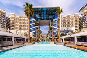 ドバイにあるFIVE Palm Luxury 1BR Apartment with Stunning Viewsのヤシの木が茂る建物の中央にあるスイミングプール