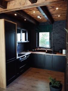 a large kitchen with black cabinets and a window at Domki TATRA HOMES z jacuzzi in Kościelisko