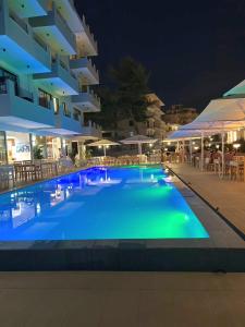 a large swimming pool in front of a building at night at oasis apartment in Sarandë