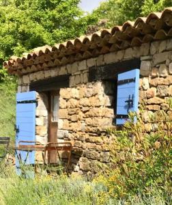 a stone building with blue shutters on it at La Bergerie du Haut Var in Bargème