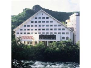 un grand bâtiment blanc à côté d'une rivière dans l'établissement Mount View Hotel - Vacation STAY 40090v, à Kamikawa