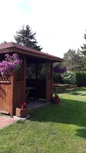 um gazebo de madeira com flores num parque em U MARTUŚKI DOMKI POKOJE POD LASEM em Stegna