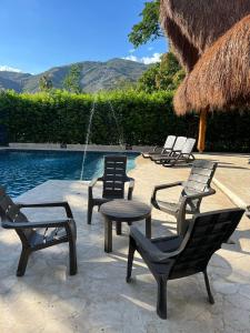 een groep stoelen en een tafel naast een zwembad bij FINCA EL ENCANTO in Santa Fe de Antioquia