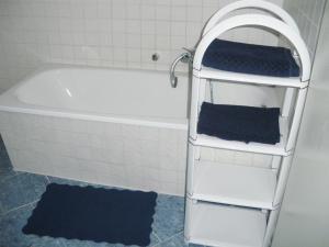 ein Badezimmer mit einer weißen Badewanne und einem weißen Regal in der Unterkunft Ferienwohnung Teutschenthal OT Langenbogen in Teutschenthal