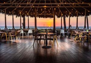 ein Restaurant mit Tischen und Stühlen vor dem Meer in der Unterkunft Departamento de lujo con vista al MAR y campo de GOLF in Barrón