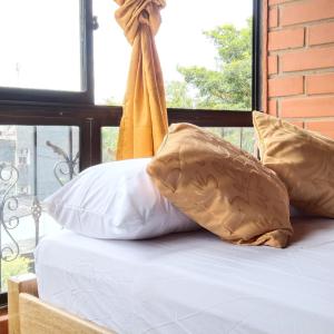een bed met witte lakens en kussens en een raam bij Mi pueblo natal Aptos y habitaciones in Necoclí