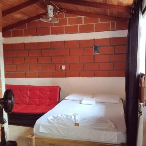 um quarto com uma cama vermelha e uma parede de tijolos em Mi pueblo natal Aptos y habitaciones em Necoclí