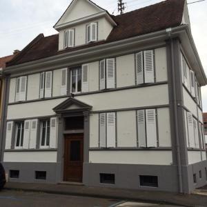 uma casa branca com persianas brancas e uma porta castanha em Salutho em Sélestat