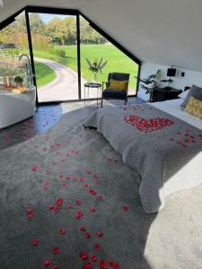 a bedroom with a bed with red rose petals on the floor at Waters Edge, Eaton in Congleton