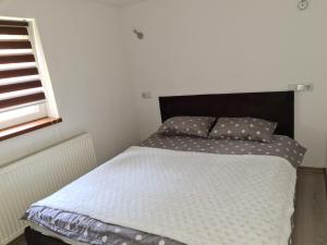 a bed with a black headboard and pillows on it at Leki Apartman in Travnik