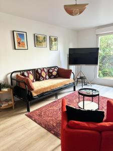a living room with a couch and a tv at Charme et Passion By UTA HOUSE in Saint-Denis