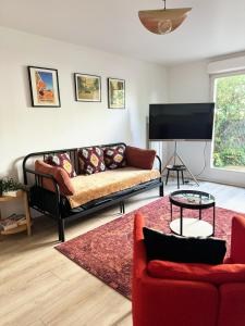 uma sala de estar com um sofá e uma televisão em Charme et Passion By UTA HOUSE em Saint-Denis