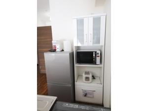 a kitchen with a refrigerator and a microwave at Chura Gahna House Tsubogawa - Vacation STAY 40171v in Naha