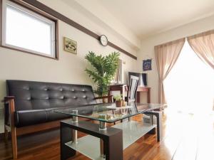 a living room with a leather couch and a glass table at Chura Gahna House Tsubogawa - Vacation STAY 40171v in Naha