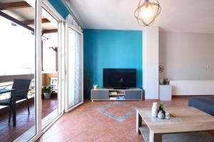 sala de estar con TV y pared azul en Our Happy Place Maisonette, en Kavala