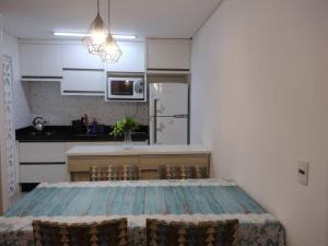 une cuisine avec une table et des chaises ainsi qu'une cuisine avec une table dans l'établissement Pertinho do Beto Carrero Jw, à Navegantes