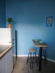uma cozinha com uma pequena mesa e uma parede azul em Joli cocon - Dijon centre ville em Dijon