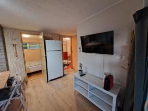 een woonkamer met een witte koelkast en een televisie bij Maci-Ház in Orfű