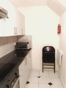 a small kitchen with a black chair in it at Close to Central London in London