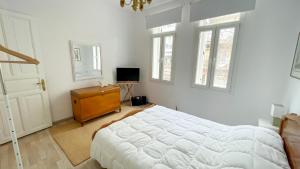 een witte slaapkamer met een bed, een dressoir en ramen bij Bright & Spacious Apartment near city center. in Thessaloniki