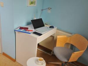 a white desk with a laptop and a chair at Holiday home Crane Coast in Kinnbackenhagen
