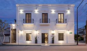 a white house with a lit up facade at night at Departamentos & Villa Monarka, 1 Block from Malecon! in La Paz