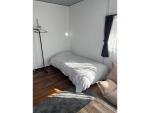 Cama blanca en una esquina de habitación en GUEST HOUSE aoshima tei - Vacation STAY 42002v, en Miyazaki