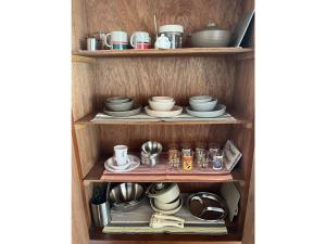 un estante con platos y tazas y platos. en GUEST HOUSE aoshima tei - Vacation STAY 42002v, en Miyazaki