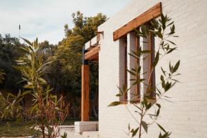 ein weißes Backsteingebäude mit einer hölzernen Pergola in der Unterkunft Tzila Lodge in Al-Fayyūm