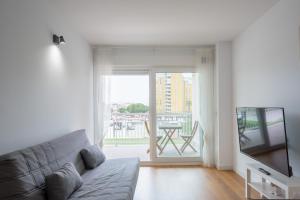 uma sala de estar com um sofá, uma televisão e uma varanda em Apartamentos en Canet al mar, junto playa y con piscina em Canet de Berenguer