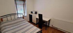 1 dormitorio con 1 cama y escritorio con microondas en Luton LU2 Ensuite room, en Luton