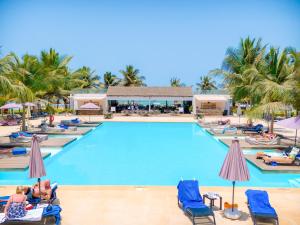 a pool at a resort with people lounging in chairs at Tamala Beach Resort in Kotu