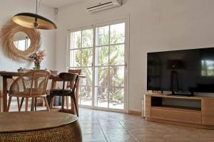 a living room with a television and a table with chairs at Oasis Golf Villa in Caleta De Fuste