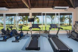 - une salle de sport avec tapis de course et matériel d'exercice devant les fenêtres dans l'établissement Flat beira-mar Jatiúca Resort by Slaviero, à Maceió