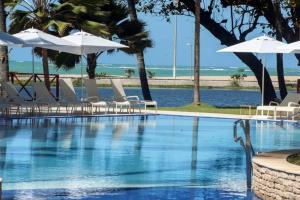 - une piscine avec des chaises et des parasols ainsi qu'une plage dans l'établissement Flat beira-mar Jatiúca Resort by Slaviero, à Maceió
