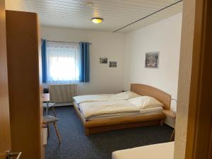a bedroom with a bed and a desk and a window at Hotel Gästehaus Sonne in Sinsheim