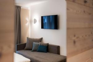 a living room with a couch and a tv on the wall at Villa Aurelia in Ortisei