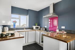 a kitchen with white cabinets and a purple wall at The Beacon, apartment next to the seafront in Herne Bay in Kent